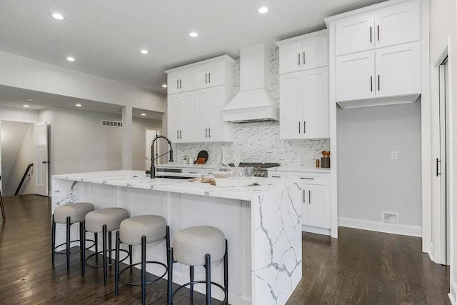 2201 W 74th St, Prairie Village, KS 66208 - kitchen featuring custom exhaust hood, a kitchen island with sink, dark wood finished floors, white cabinetry, and recessed lighting