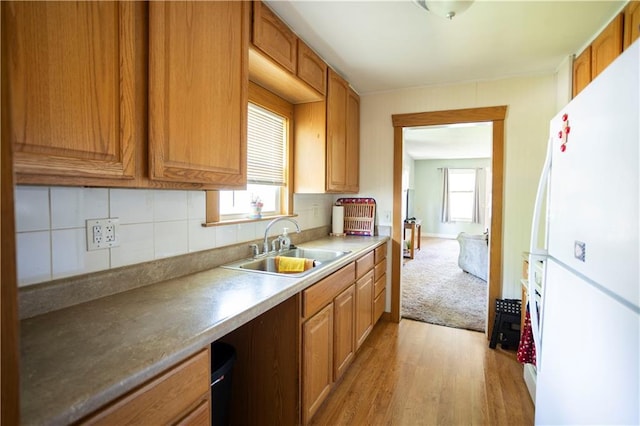 1619 W College St, Independence, MO 64050 - kitchen with freestanding refrigerator, light wood-style floors, tasteful backsplash, and brown cabinets
