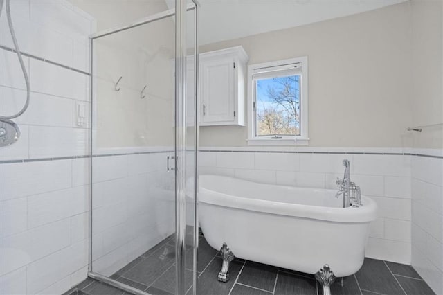 11412 Foster St, Overland Park, KS 66210 - bathroom featuring tile walls, tile patterned flooring, a shower stall, a soaking tub, and wainscoting
