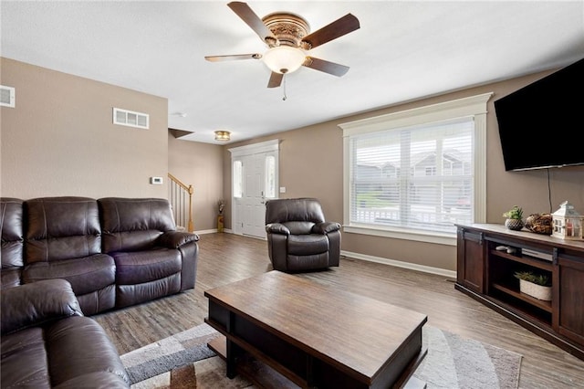 12318 N Wayne Ave, Kansas City, MO 64165 - living room featuring wood finished floors, a ceiling fan, and stairway