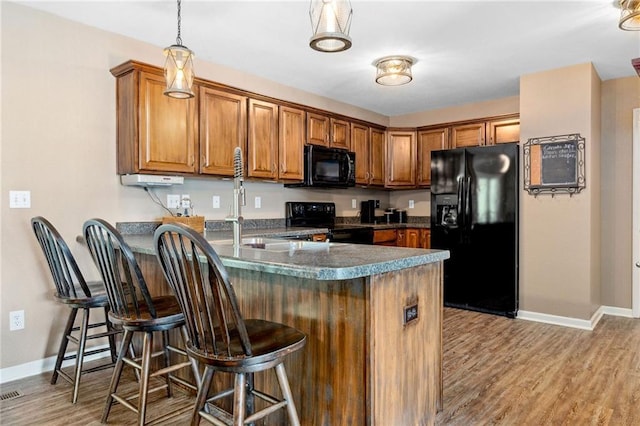 12318 N Wayne Ave, Kansas City, MO 64165 - kitchen with black appliances, brown cabinetry, a peninsula, and light wood-type flooring
