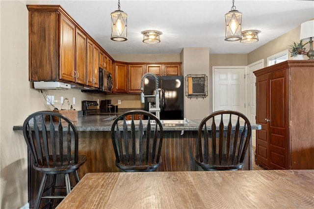 12318 N Wayne Ave, Kansas City, MO 64165 - kitchen with black appliances, a peninsula, dark countertops, and hanging light fixtures
