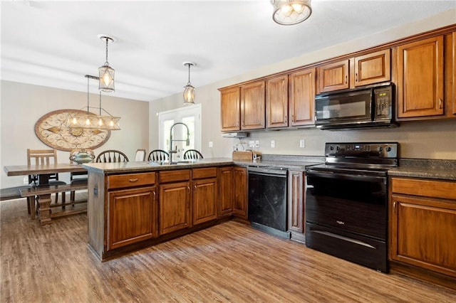 12318 N Wayne Ave, Kansas City, MO 64165 - kitchen with black appliances, brown cabinets, wood finished floors, and a peninsula