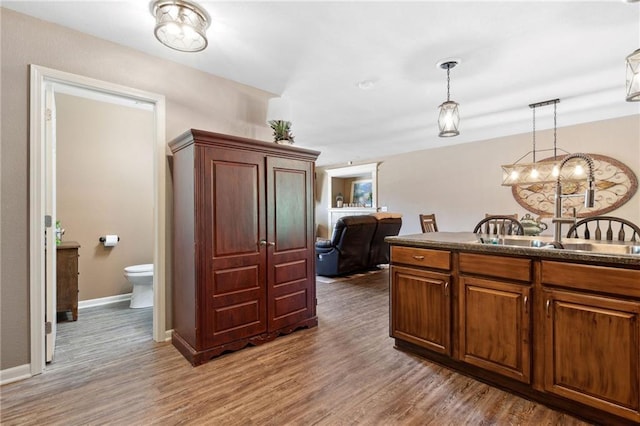12318 N Wayne Ave, Kansas City, MO 64165 - kitchen featuring wood finished floors, pendant lighting, dark countertops, and brown cabinets