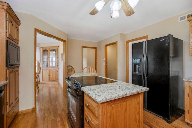 18209 E Moorland St, Pleasant Hill, MO 64080 - kitchen featuring black appliances, light wood-style floors, a kitchen island, a ceiling fan, and brown cabinetry