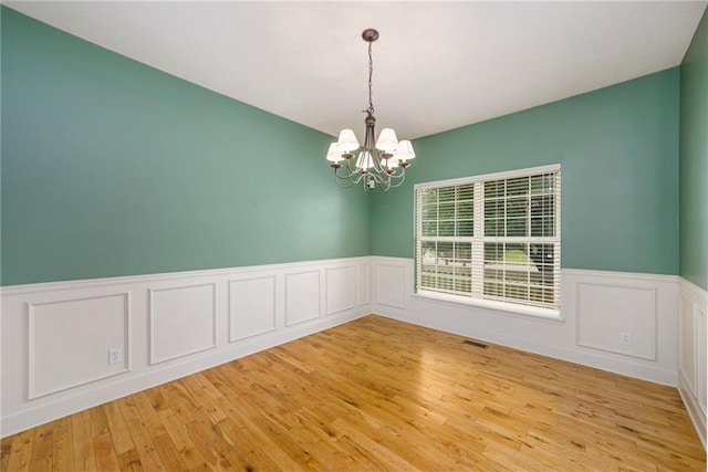 1905 160th St, Basehor, KS 66007 - unfurnished room with a chandelier, wainscoting, light wood-style flooring, and a decorative wall