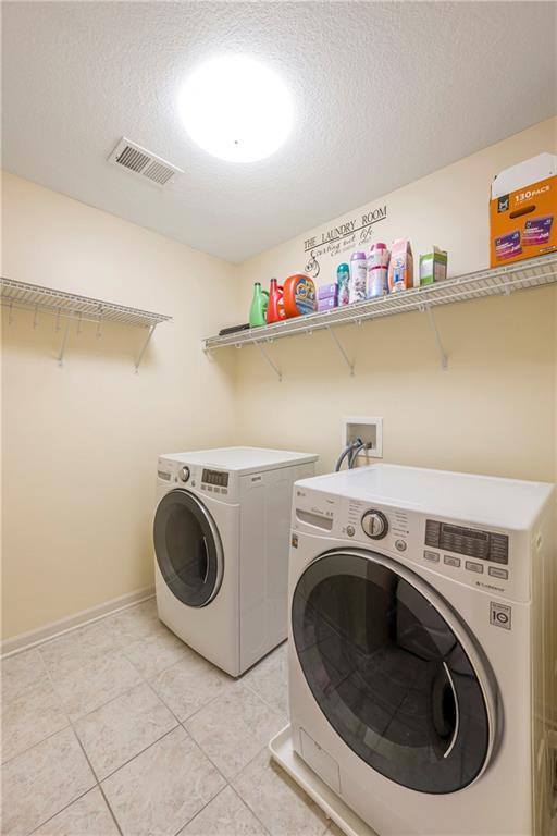 1905 160th St, Basehor, KS 66007 - laundry area with washing machine and dryer, light tile patterned floors, and a textured ceiling