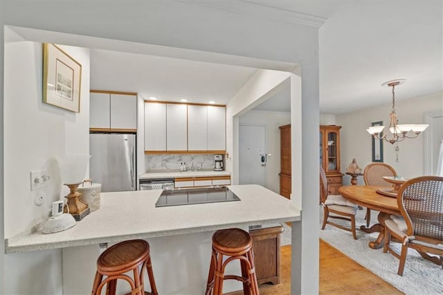 5137 W 75th St, Prairie Village, KS 66208 - kitchen featuring stainless steel appliances, a peninsula, a breakfast bar area, light countertops, and a chandelier