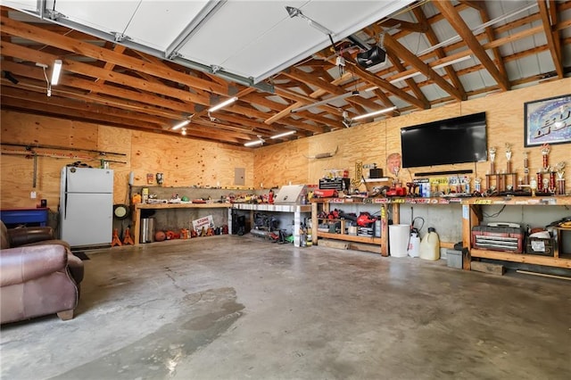 39103 New Lancaster Rd, Lacygne, KS 66040 - garage with freestanding refrigerator, a workshop area, and a garage door opener