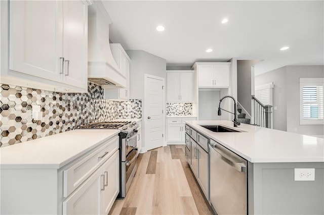 23506 E 10th St S, Independence, MO 64056 - kitchen featuring stainless steel appliances, custom range hood, light wood finished floors, white cabinets, and light countertops