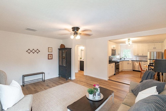 319 E 12th St, Ottawa, KS 66067 - living area featuring light wood-style floors, ceiling fan, and arched walkways