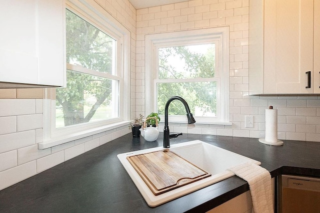 319 E 12th St, Ottawa, KS 66067 - kitchen view of dark countertops, white cabinets, backsplash, and dishwashing machine