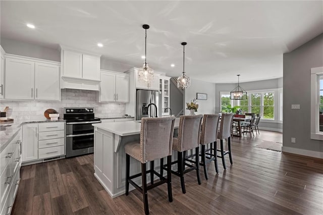 6417 County Road 10508th Rd, Rich Hill, MO 64779 - kitchen with appliances with stainless steel finishes, tasteful backsplash, white cabinets, dark wood-type flooring, and a kitchen island with sink