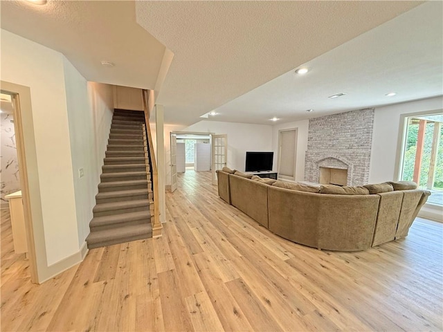 6112 N Mattox Rd, Kansas City, MO 64151 - living area with light wood finished floors, stairway, a large fireplace, recessed lighting, and a textured ceiling