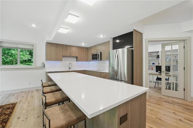 6112 N Mattox Rd, Kansas City, MO 64151 - kitchen with stainless steel appliances, light countertops, a kitchen breakfast bar, light wood-type flooring, and recessed lighting