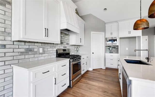 6045 Apache Dr, Shawnee, KS 66226 - kitchen with appliances with stainless steel finishes, premium range hood, decorative backsplash, wood finished floors, and decorative light fixtures