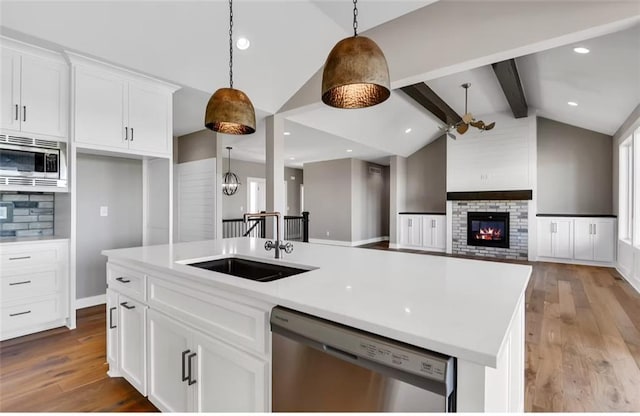 6045 Apache Dr, Shawnee, KS 66226 - kitchen with appliances with stainless steel finishes, light wood finished floors, white cabinets, a glass covered fireplace, and ceiling fan