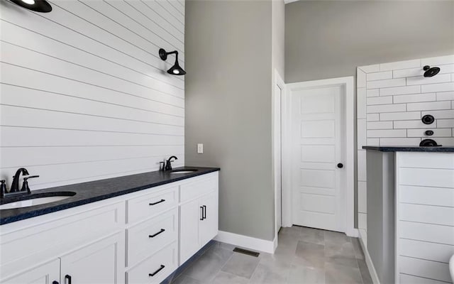 6045 Apache Dr, Shawnee, KS 66226 - bathroom featuring double vanity, wooden walls, and tiled shower