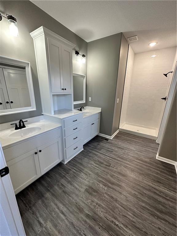 318 NE 51st Rd, Warrensburg, MO 64093 - bathroom featuring wood finished floors, a shower stall, and two vanities