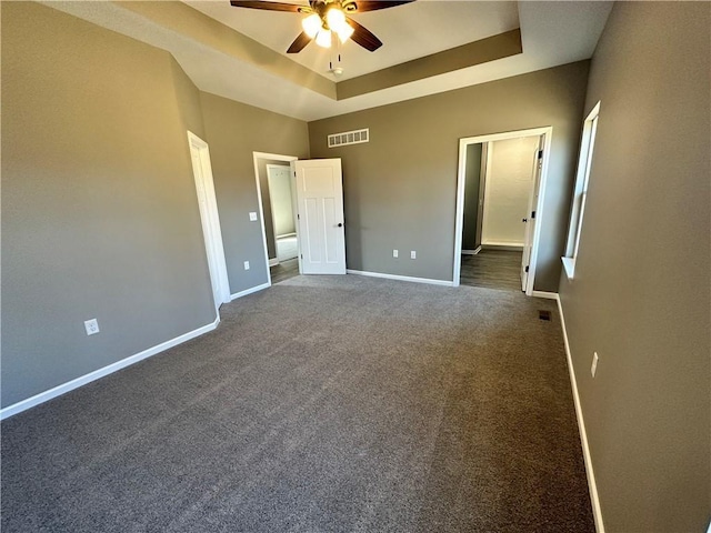318 NE 51st Rd, Warrensburg, MO 64093 - unfurnished bedroom with a tray ceiling, dark carpet, and ceiling fan