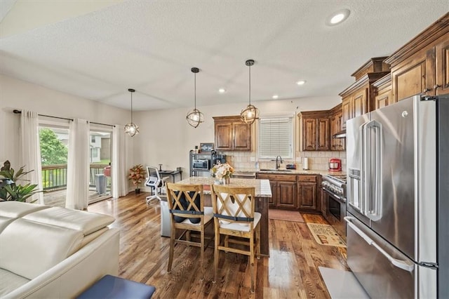 18783 W 165th St, Olathe, KS 66062 - kitchen with high end appliances, a center island, decorative backsplash, wood finished floors, and a textured ceiling