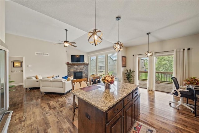 18783 W 165th St, Olathe, KS 66062 - kitchen featuring a fireplace, dark wood-style flooring, a breakfast bar area, ceiling fan, and pendant lighting