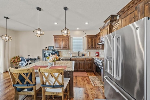 18783 W 165th St, Olathe, KS 66062 - kitchen featuring high end appliances, light wood-style flooring, decorative backsplash, a center island, and light stone countertops
