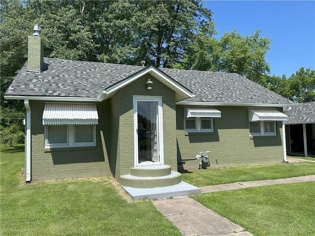 1047 N Lynn St, Nevada, MO 64772 - bungalow featuring brick siding, a chimney, a front yard, and roof with shingles
