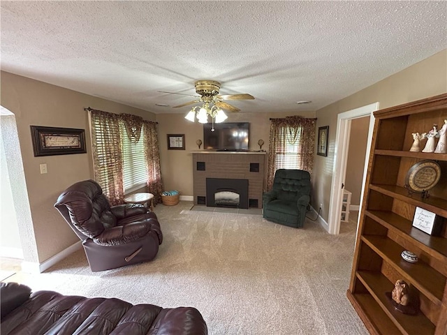 1047 N Lynn St, Nevada, MO 64772 - carpeted living room featuring a fireplace, a ceiling fan, and a textured ceiling