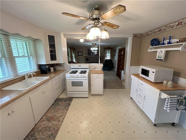 1047 N Lynn St, Nevada, MO 64772 - kitchen with white appliances, white cabinets, light countertops, and ceiling fan