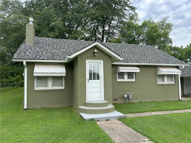 1047 N Lynn St, Nevada, MO 64772 - view of front of home featuring a front lawn, brick siding, a chimney, and roof with shingles