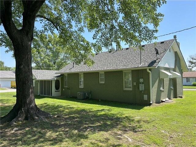 1047 N Lynn St, Nevada, MO 64772 - rear view of house with a lawn, brick siding, and roof with shingles