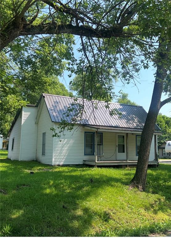 229 E Bates St, Drexel, MO 64742 - view of front of house with a front yard, a metal roof, and a porch