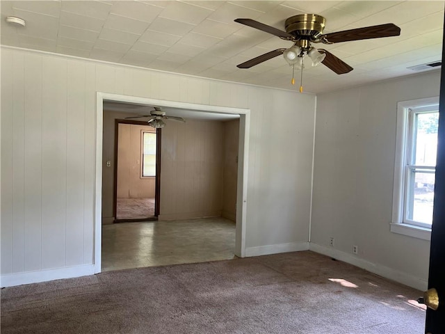 229 E Bates St, Drexel, MO 64742 - carpeted empty room with healthy amount of natural light, a smoke detector, ceiling fan, and wooden walls