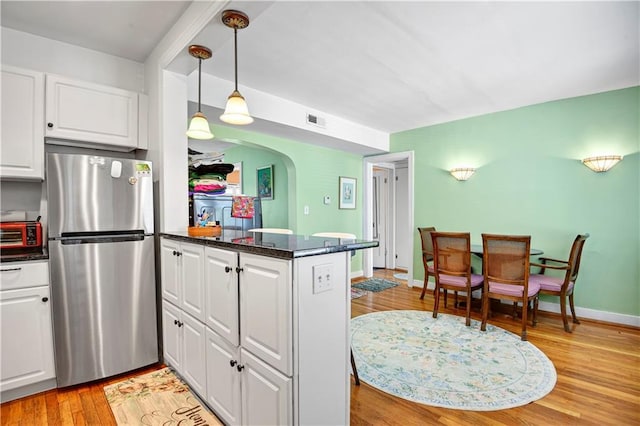 212 Emanuel Cleaver Ii Blvd Unit 2West, Kansas City, MO 64112 - kitchen with freestanding refrigerator, arched walkways, white cabinetry, and light wood finished floors