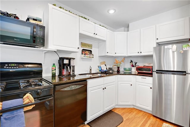 212 Emanuel Cleaver Ii Blvd Unit 2West, Kansas City, MO 64112 - kitchen with black appliances, white cabinetry, dark stone counters, and recessed lighting