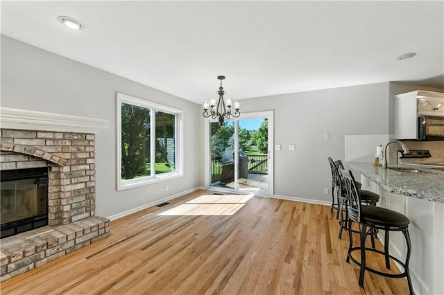 503 Amesbury Dr, Smithville, MO 64089 - dining room featuring light wood-style flooring, a brick fireplace, and a chandelier