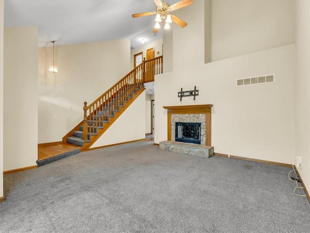 15409 Conser St, Overland Park, KS 66223 - unfurnished living room with carpet flooring, ceiling fan, stairway, a stone fireplace, and a high ceiling