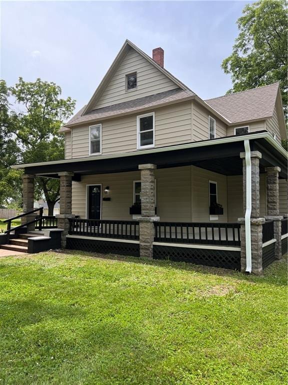 112 N High St, Butler, MO 64730 - view of front of home with a porch, a chimney, and a front lawn