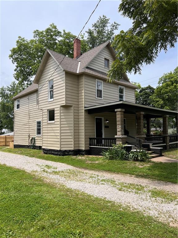 112 N High St, Butler, MO 64730 - view of side of home with a chimney, a porch, a yard, and roof with shingles