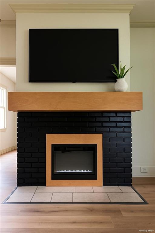 112 N High St, Butler, MO 64730 - detailed view of a brick fireplace, crown molding, and wood finished floors