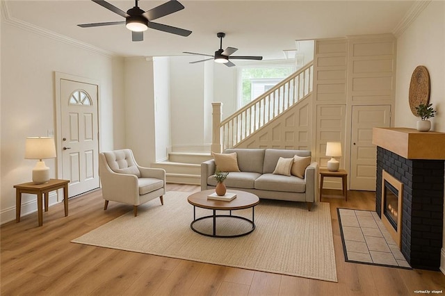 112 N High St, Butler, MO 64730 - living room featuring ceiling fan, light wood-type flooring, crown molding, stairs, and a fireplace