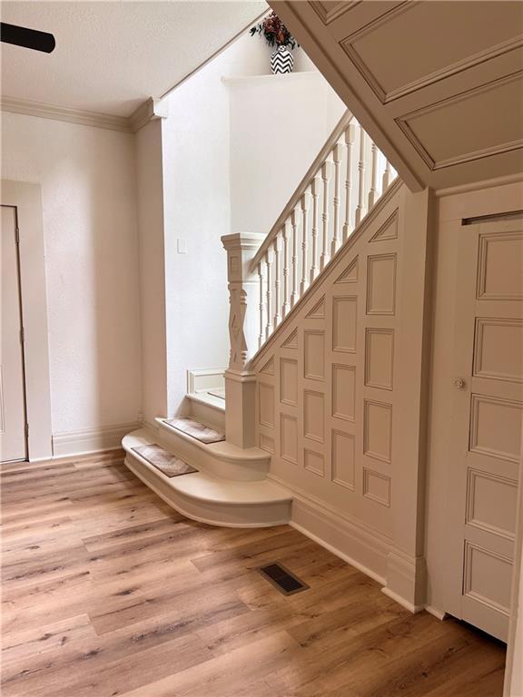 112 N High St, Butler, MO 64730 - stairway with wood finished floors and ornamental molding