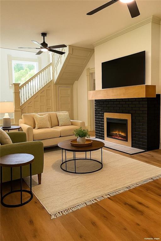 112 N High St, Butler, MO 64730 - living room featuring a ceiling fan, wood finished floors, ornamental molding, and a fireplace