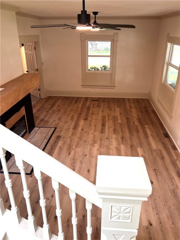 112 N High St, Butler, MO 64730 - empty room with ceiling fan, light wood-style floors, crown molding, and stairs