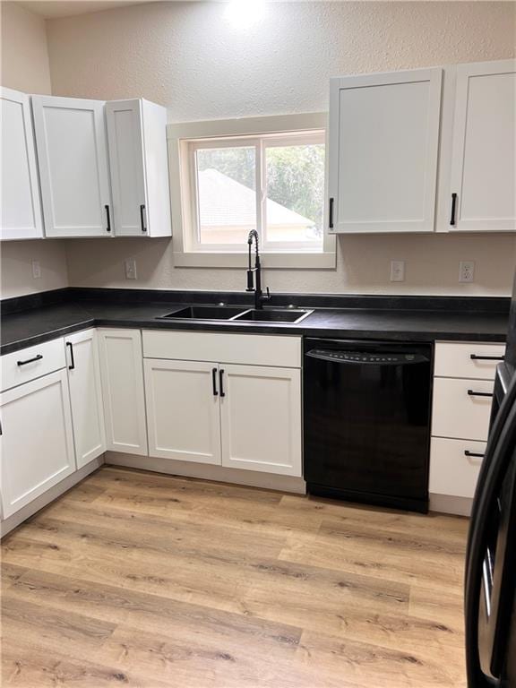 112 N High St, Butler, MO 64730 - kitchen with black dishwasher, white cabinetry, dark countertops, a textured wall, and light wood-style floors