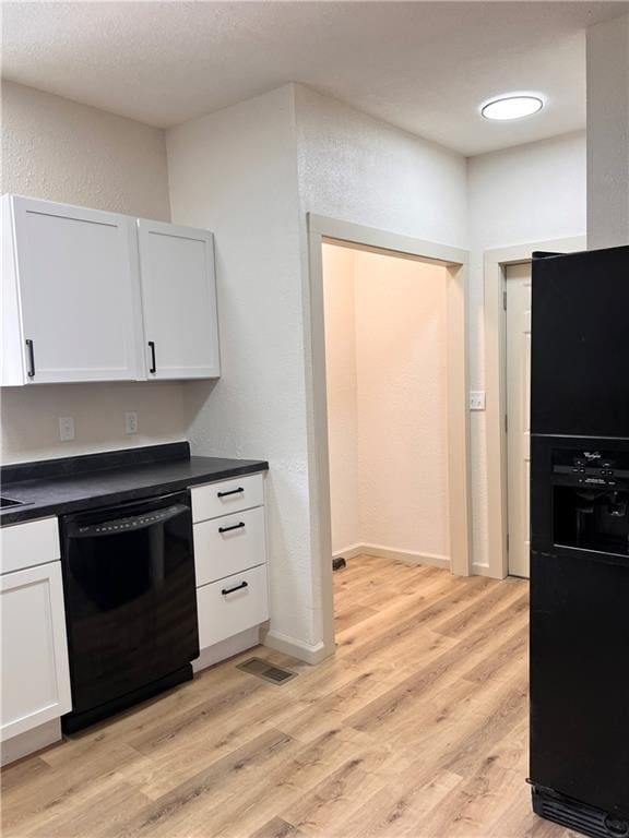 112 N High St, Butler, MO 64730 - kitchen featuring black appliances, a textured wall, dark countertops, light wood finished floors, and white cabinetry