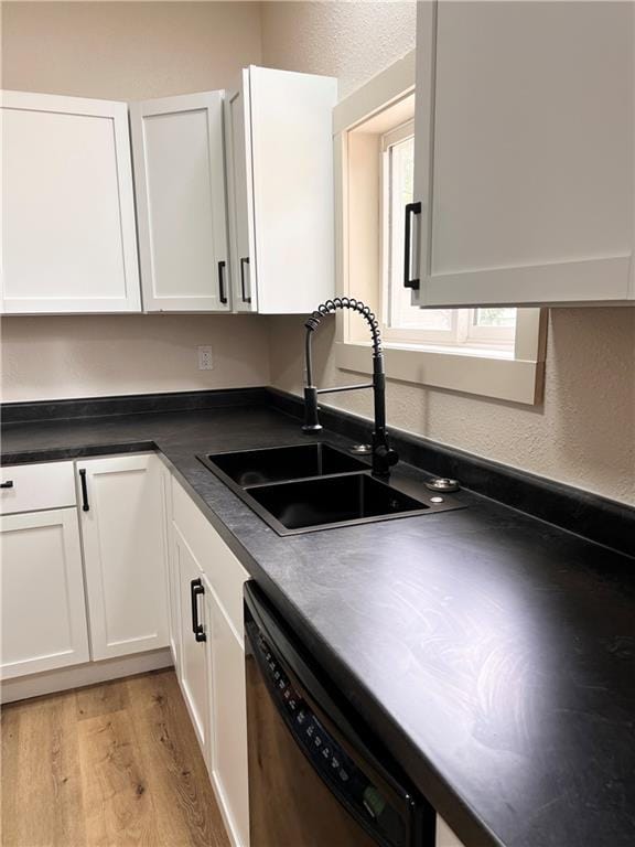112 N High St, Butler, MO 64730 - kitchen featuring dishwasher, white cabinets, light wood-type flooring, dark countertops, and a textured wall
