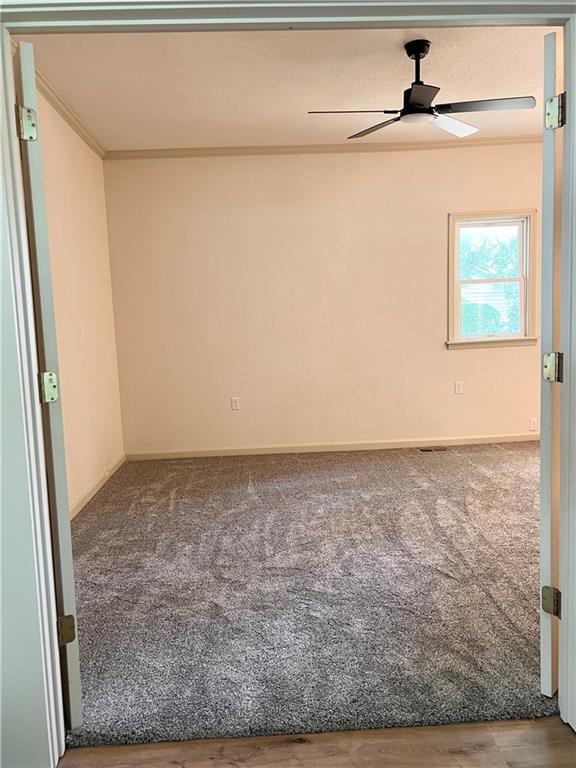 112 N High St, Butler, MO 64730 - carpeted spare room with a ceiling fan and crown molding