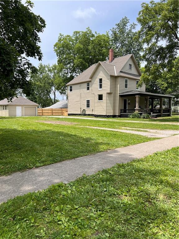 112 N High St, Butler, MO 64730 - view of side of property featuring a garage and a chimney